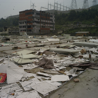 映秀鎮中已拆除的板房。中國所稱的板房就是台灣的組合屋。板房拆除後的處理也是一大難題，因為是由防火材質製成，拆除後不能焚燒，造成環保的問題。圖片後方的電塔，都是地震後重建的。