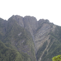 圖中所拍攝的對象為位於玉山主峰與南峰間之三叉峰。從圖中可以看見三叉峰的峰頂和山腰間呈現截然不同的岩層排列，大致而言，峰頂的部分與此坡面呈現崖坡的關係，但在山腰的部分則是以斜交坡為主。從如此截然不同的位態則可得知此區域在抬升的過程中，不同高度的岩層所受到的應力作用方向很可能是不一致的。另外，不同位態對於風化作用的反應結果也不相同，從本圖即可得知兩者的差異。