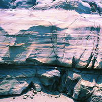 砂岩層剖面的平行層理。照片中所顯示的層理多為平行排列，其中有二層顏色較為褐色，顯示此層之中含有不同的化學成分如鐵，受到水溶解之後沈澱在表面使顏色與其他層不同。垂直於層理有許多裂隙，風化侵蝕營力容易沿這些裂隙面對岩層產生破壞。