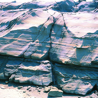 厚層砂岩堆積層中有時會夾有岩性較為軟弱的泥岩或頁岩，在岩性不同的差異下，泥岩、頁岩會容易受侵蝕消失而凹陷，如照片中岩層剖面較為凹陷的部分。而沿節理面被破壞崩落的岩石掉落於下方。