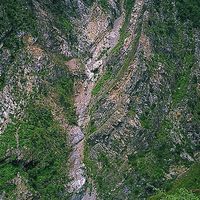 大甲溪河岸的邊坡崩塌，滑落岩屑直達溪谷。照片中的裸露岩層，呈現出類似向斜的地質構造。