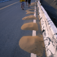 攝於2005年4月3日。風吹沙地景，夏季有沙順著崖坡流入海中的沙瀑景象、冬季有沙沿著崖坡飛向崖頂的景象。照片中可見風吹沙被搬至崖頂公路上堆積。