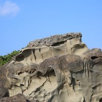 照片中的景觀大概可以分為不易被侵蝕的珊瑚礁岩、形狀不規則的結核以及容易受侵蝕的砂岩，三者之間有明顯的分層，也可以看到不同岩性在同樣的作用力下，呈現出不同樣貌。